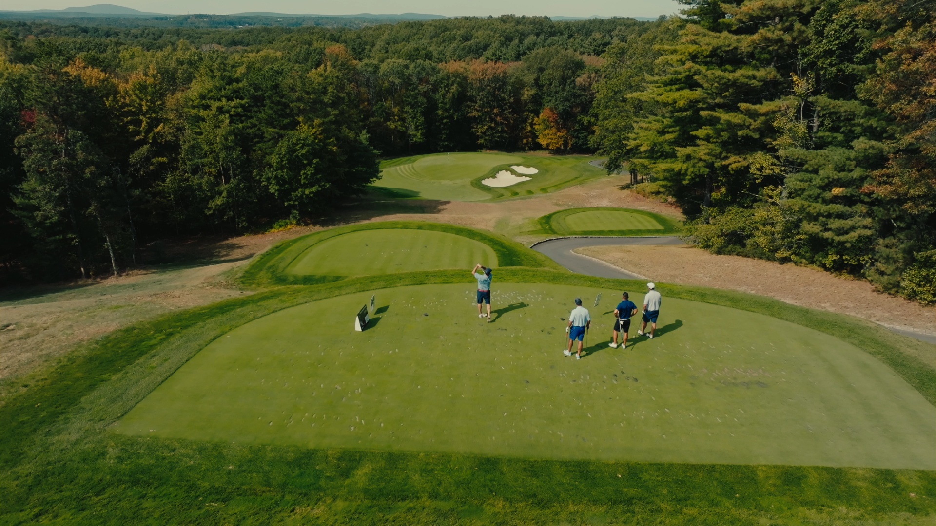 Aerial view of a foursome teeing off with the green ahead